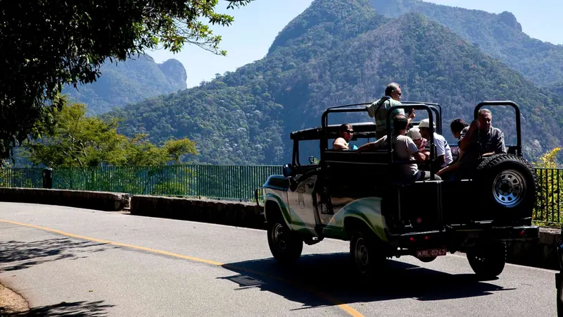 An open-top jeep carrying visitors along a mountain road in Tijuca Forest