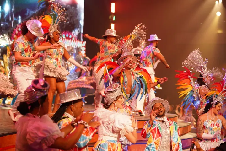 Performers in bright costumes on stage at the Roxy Dinner Show
